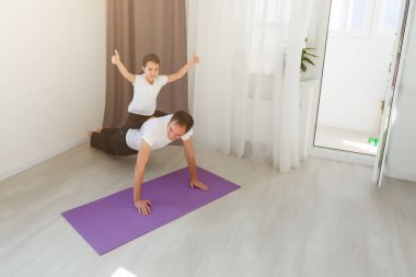 Babası antrenman yapıyor, kızıyla tek kollu tahta yapıyor. Evde. 