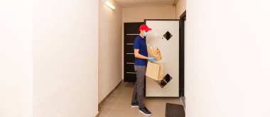 Karton kutuları plastik eldiven ve maskeyle taşıyan teslimatçı. İnternetten alışveriş 