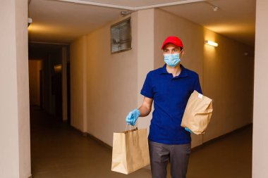Karton kutuları plastik eldiven ve maskeyle taşıyan teslimatçı. İnternetten alışveriş 