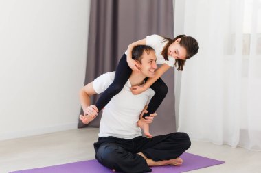 Babası antrenman yapıyor, kızıyla tek kollu tahta yapıyor. Evde. 