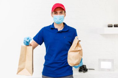 Karton kutuları plastik eldiven ve maskeyle taşıyan teslimatçı. İnternetten alışveriş 