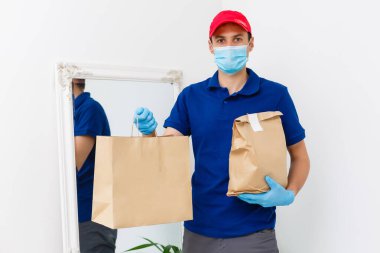 Karton kutuları plastik eldiven ve maskeyle taşıyan teslimatçı. İnternetten alışveriş 