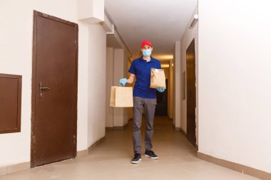 Karton kutuları plastik eldiven ve maskeyle taşıyan teslimatçı. İnternetten alışveriş 