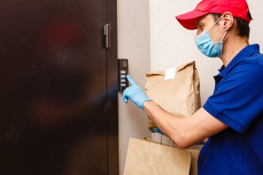 Karton kutuları plastik eldiven ve maskeyle taşıyan teslimatçı. İnternetten alışveriş 