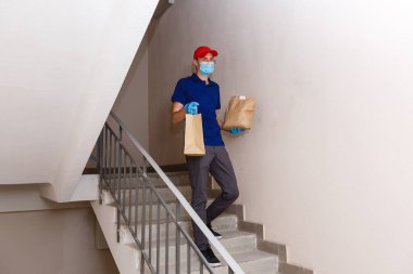 Karton kutuları plastik eldiven ve maskeyle taşıyan teslimatçı. İnternetten alışveriş 