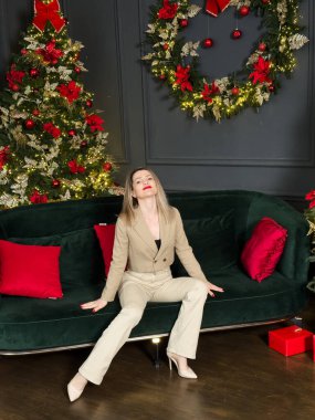 Sıcak bir tatil ortamında eğlenen bir kadın. Genç bir kadın, süslü bir Noel ağacıyla süslenmiş rahat bir oturma odasında dinleniyor. Yüksek kalite fotoğraf