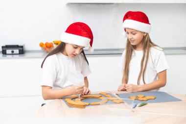 Çocuklar Noel kurabiyesi evini masanın üzerine dekore ettiler. Yüksek kalite fotoğraf