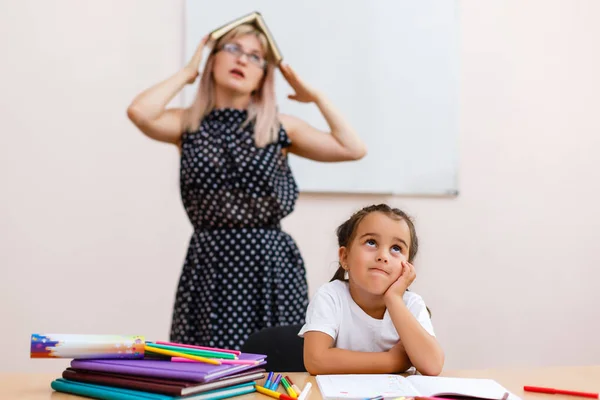 Trauriges Madchen In Der Schule Am Schreibtisch Sitzend Und Muder Lehrer Mit Buch Stehend Menschen Kindheit Stock Photo 212315860