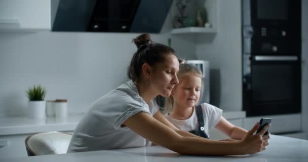 赤ん坊の女の子を持つ乳母が台所に座っており ビデオリンクを介して親戚と通信しています ビデオで親族を呼び出す — ストック動画