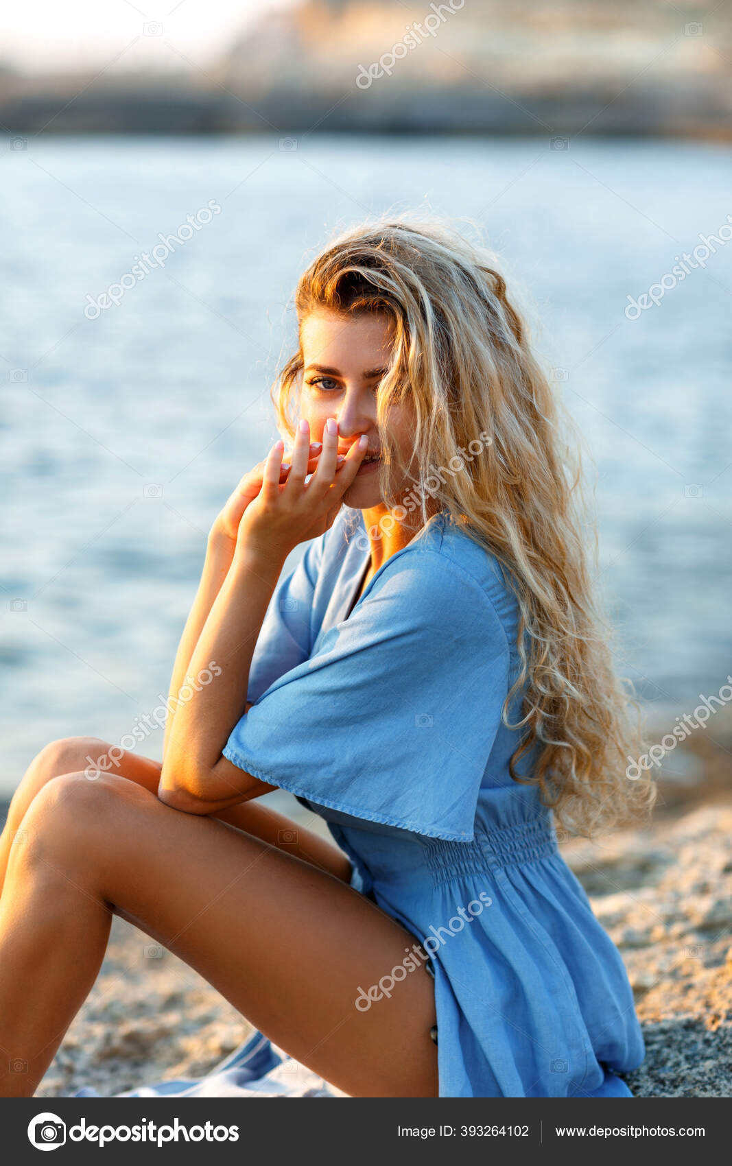 一个年轻的金发女子的画像 她在日落时坐在海边放松下来 图库照片 C Kanstantsinzzz