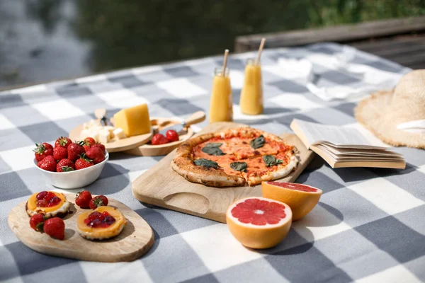 Göl kenarında doğada nefis bir yaz pikniği. Pizza, şeker, dut ve kitap okuma ile piknik. Açık hava pikniği. Yemeğe odaklan..