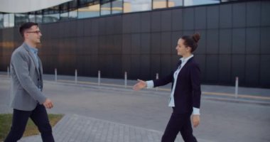 Neşeli gülümseyen genç iş arkadaşları iş merkezinin yakınında buluşup iş konularını konuşuyorlar. Sokaktaki meslektaşların iletişimi. 