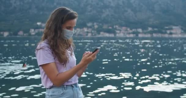 Šťastná žena turista v ochranné masce komunikuje prostřednictvím videohovoru s přáteli. Pohled na záliv a hory. Žena portrét close-up. — Stock video