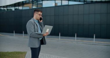 Takım elbiseli bir adam dizüstü bilgisayar üzerinde çalışıyor ve şehir merkezinde telefonla konuşuyor. Yapacak işlerim var..