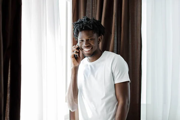 Aşırı neşeli Afro-Amerikan milenyum adamı gülüyor keyifli cep telefonu sohbetleri yapıyor, mutlu çift ırklı erkek gülüşleri akıllı telefon görüşmelerine katılıyor, modern bir cihaz kullanarak konuşuyor, iyi bir bağlantı konsepti.