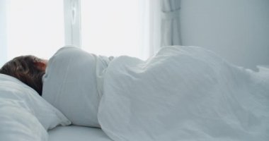 Genç bir kadın evinde uyuyor. Ev rahatlığı. Geniş pencere görünümü, arka plan