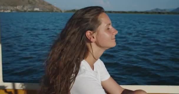 Une femme heureuse aux cheveux bouclés flotte sur un bateau sur la rivière. Ses cheveux soufflent dans le vent. Portrait féminin — Video