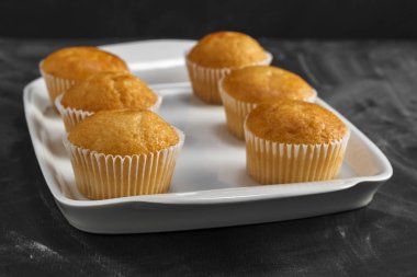 Karanlık bir arka plan üzerinde beyaz bir tabakta cupcakes