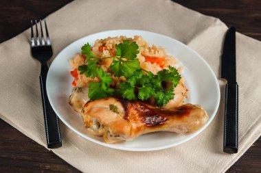 Fırında tavuk baget ve sebzeli pilav, maydanoz bir plaka üzerinde bir peçete