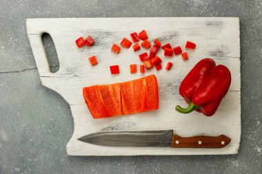 Kırmızı dolmalık biber beyaz tahta üzerinde bıçakla dilimlenmiş.