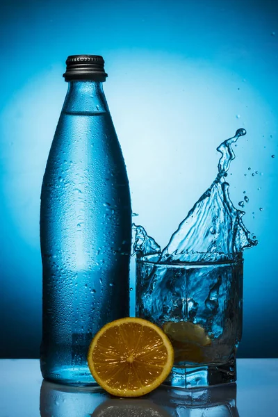 Misted bottle of water with spray in a glass and lemon