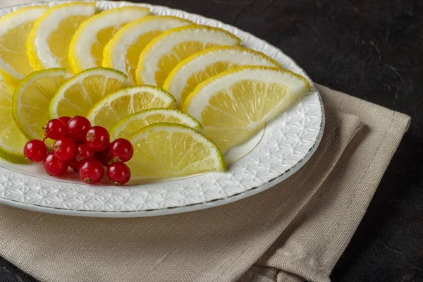 Zitrus-Snack aus Limette und Zitrone und einem Zweig Johannisbeeren mit einer beigen Serviette — Stockfoto