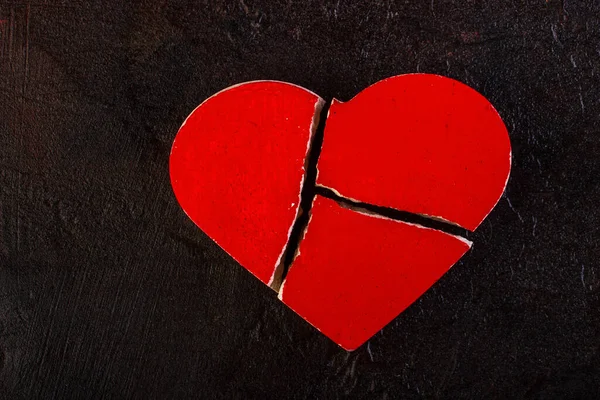 Red broken heart against a dark background