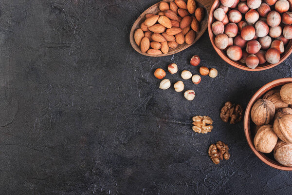 Walnut, hazelnuts and almonds in a spoon against a dark background