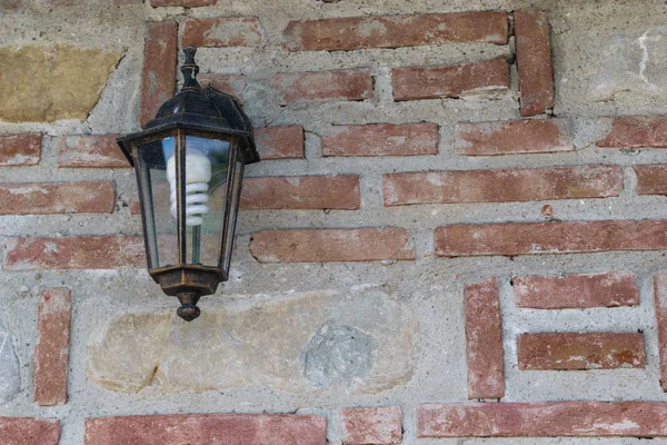 exterior light fixture mounted on brick wall with copy space. Energy saving light bulb installed