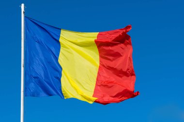 Romanya bayrağı rüzgarda hareketli yazı. Açık mavi arka plan ile rüzgarda sallayarak Romen kırmızı, yeşil ve mavi bayrak.