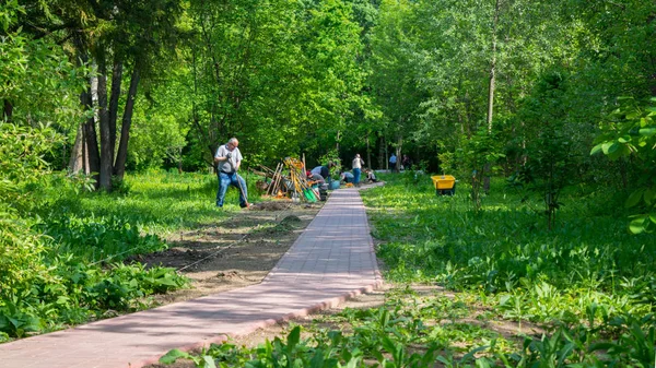 Bükreş, Romanya - 04 Mayıs 2019: Bükreş'teki Botanik Bahçesi'ndeki parkta çiçek tarhını korumak için çalışan insanlar.