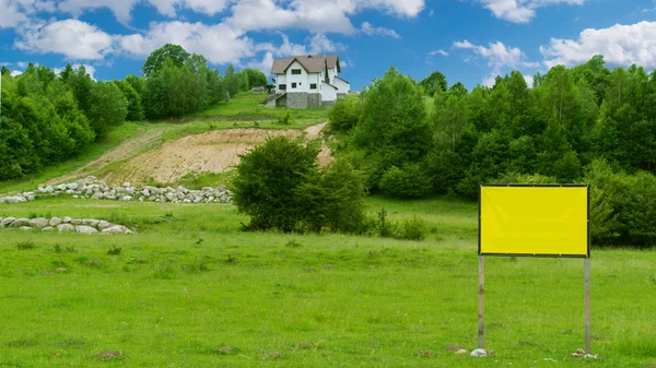 Tepenin yukarısında yeşil ağaçlarla çevrili bir ev ve ön plana metin eklemek için bir panel