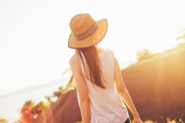 İyi günler. Şapkalı bir kız günbatımında görünüyor. Sıcak yaz gecesi. 