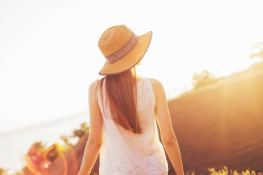 Şapkalı bir kız günbatımında görünüyor. Sıcak yaz gecesi. gün batımında denizin üzerinde seyir