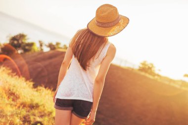 Şapkalı bir kız günbatımında görünüyor. Sıcak yaz gecesi. gün batımında hasır şapkalı bir kız sıcak yaz fotoğrafı.