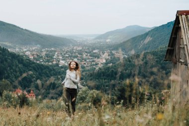 Seyir ve dağlarda bir çimenlikte atlama sırasında gülümseyen oynak genç kız