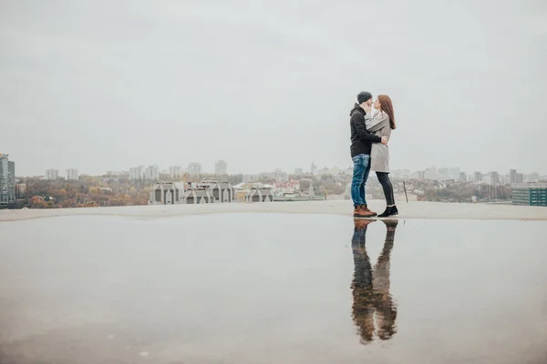 在城市全景的背景下 在高楼屋顶上的爱的夫妇 爱在水的倒影中 — 图库照片