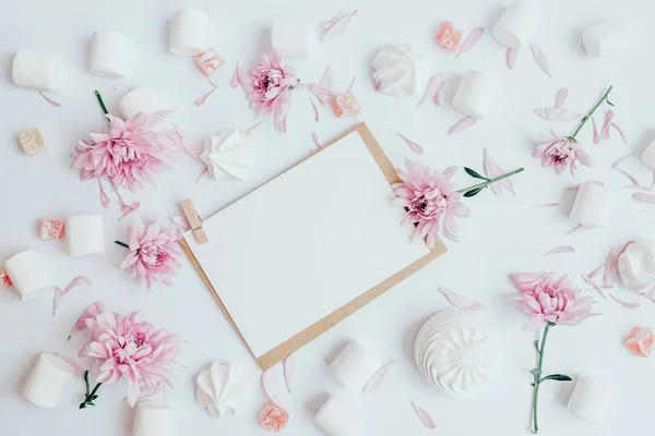Beyaz sayfa üzerinde tablo. Beyaz şekerlemeler ve pembe çiçek çevresinde. Düz beyaz arka plan üzerinde yatıyordu