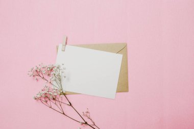 Çiçekler, zarf ve beyaz Not kartı. Üst görünüm ve pembe arka plan düz yatıyordu
