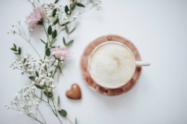 Bir fincan kahve krem ve beyaz arka plan üzerinde çiçekler. Bahar düz kompozisyon yatıyordu