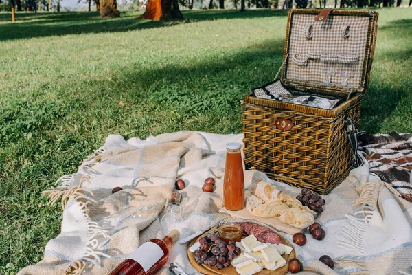 Ekmek, meyve, peynir ve bir şişe kırmızı şarap ile güneşli bir günde tarlada piknik öğle yemeği.