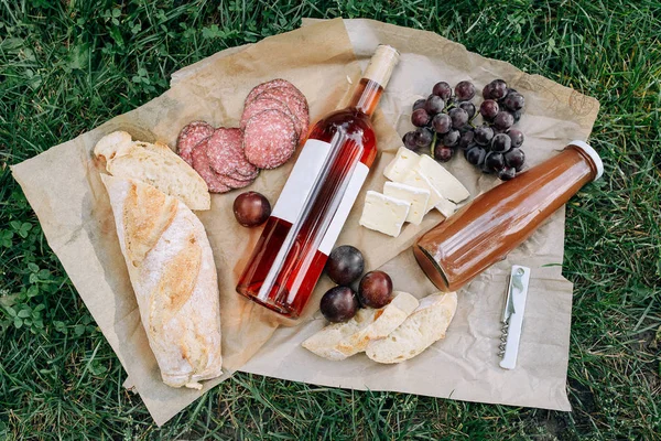 サラミ チーズ ブドウ 公園の芝生の上にローズワインとジュースのボトル 食べ物と飲み物のコンセプト — ストック写真