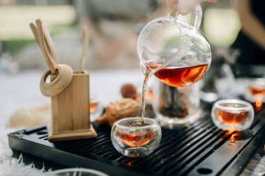 Cam çaydanlıkta kırmızı çay fincanlara dökülür. Sabah parkta çay seremonisi var. Çay seremonisinin atmosferi.