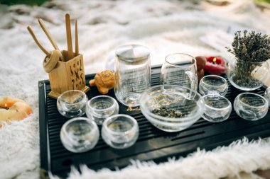 Ahşap tepside çay seremonisi için cam eşyalar. Mumlar ve lavantalar bir vazoda atmosfer için.