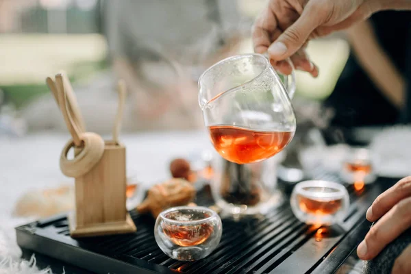 Bir erkek eli cam çaydanlığı taze demlenmiş kırmızı çayla tutar..