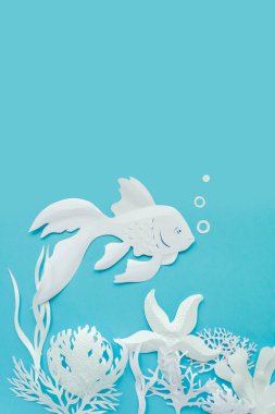 Mavi arka plan üzerinde beyaz kağıt kesim kadar balık kapatın. Okyanus ve denizaltı dünyanın farklı sakinleri, mercan ve deniz yıldızı