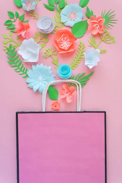 Paper bag of different paper flower on a pink background. Shopping. Top view. Flat lay