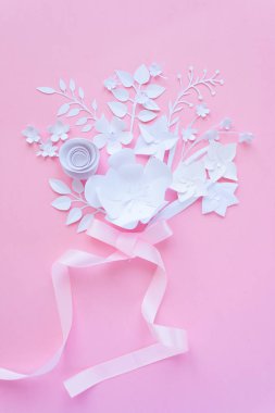 Çiçek aranjmanı. Çiçek, parfüm, pembe bir arka plan üzerinde pembe kurdele ile beyaz kağıt çiçek buketi. Kağıttan kesilmiş