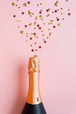Pembe bir arka plan üzerinde farklı yıldız payetler şampanya şişesiyle. Açık şampanya kavramı. Düz yatıyordu.