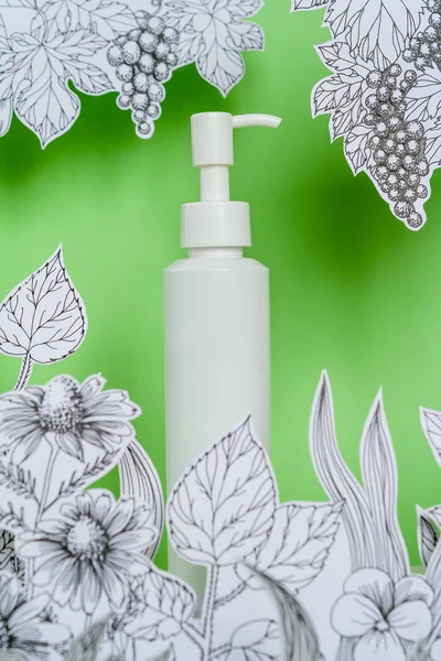 Mock-up realistic blank tubes for cosmetics. Concept natural herbal cosmetics with drawing paper flowers with painted leaves and stems on green background